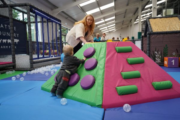 green soft play structure with a mom and boy